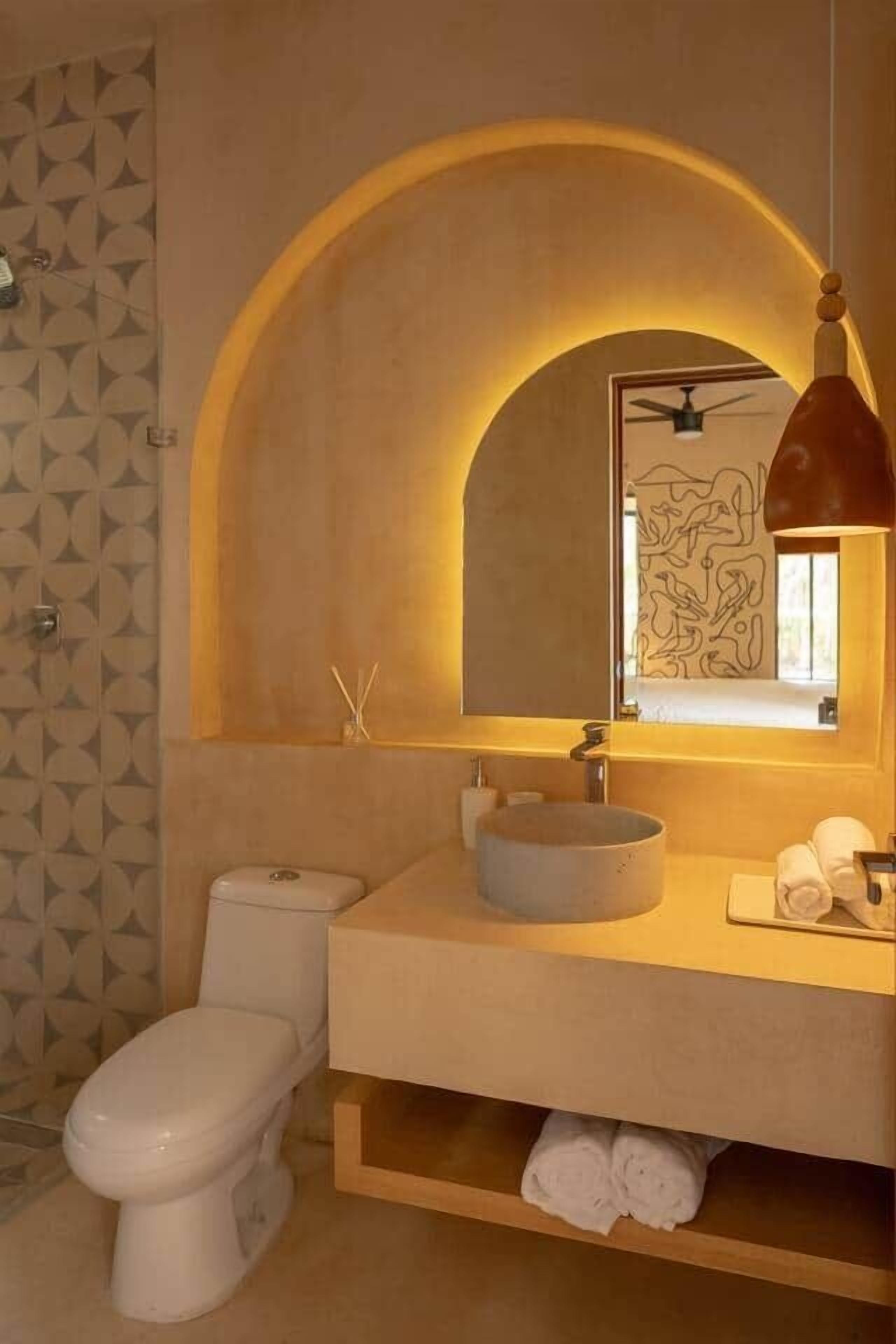 Baño con inodoro, lavabo y espejo.