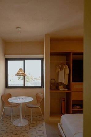 A room with a bed, a round table with two chairs, a wardrobe, and a window with a view.
