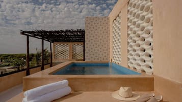 Un área de piscina en la azotea con vistas al paisaje, una pérgola y una pared con diseño geométrico.