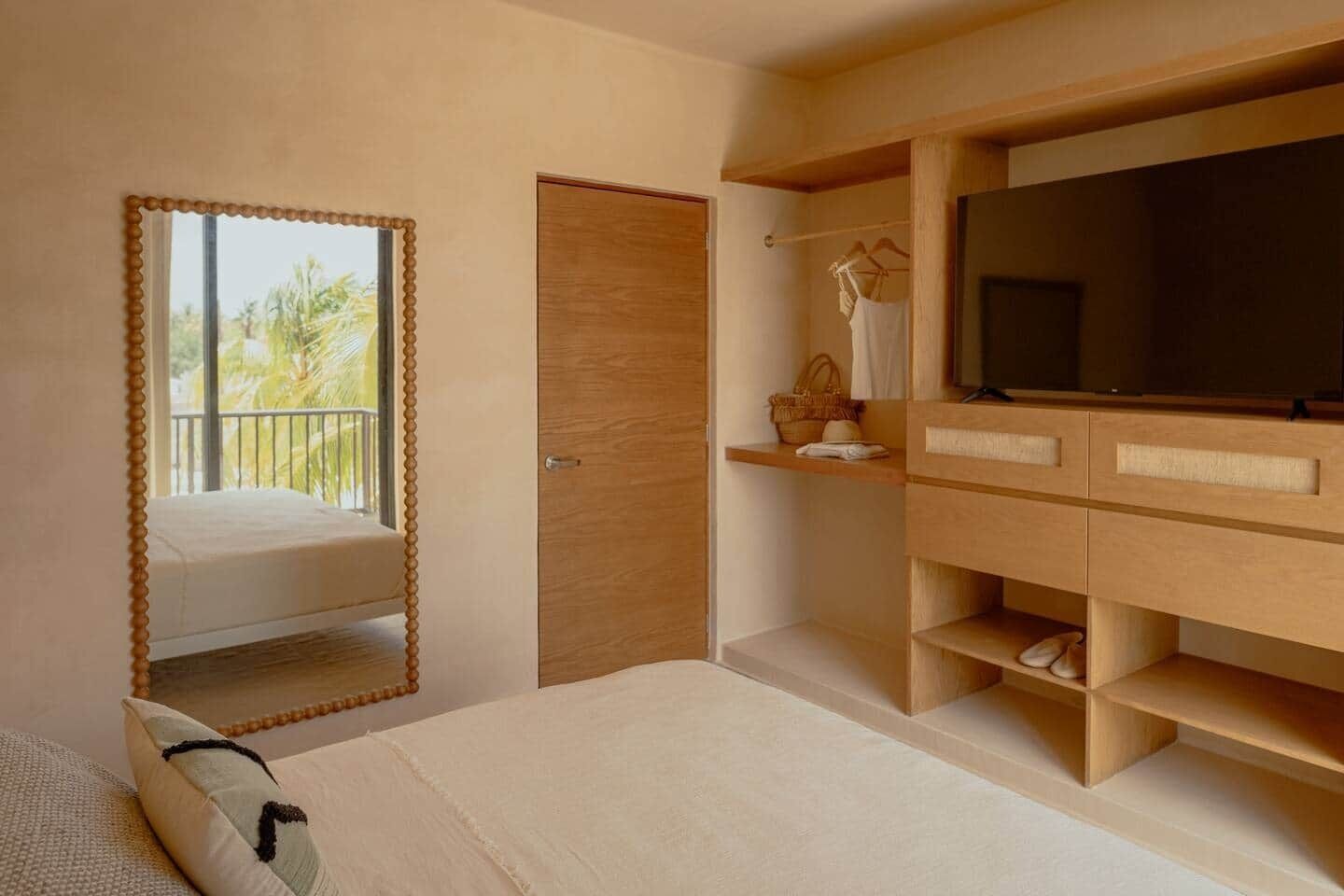 A bedroom with a bed, a TV, wooden furniture, and a balcony view.