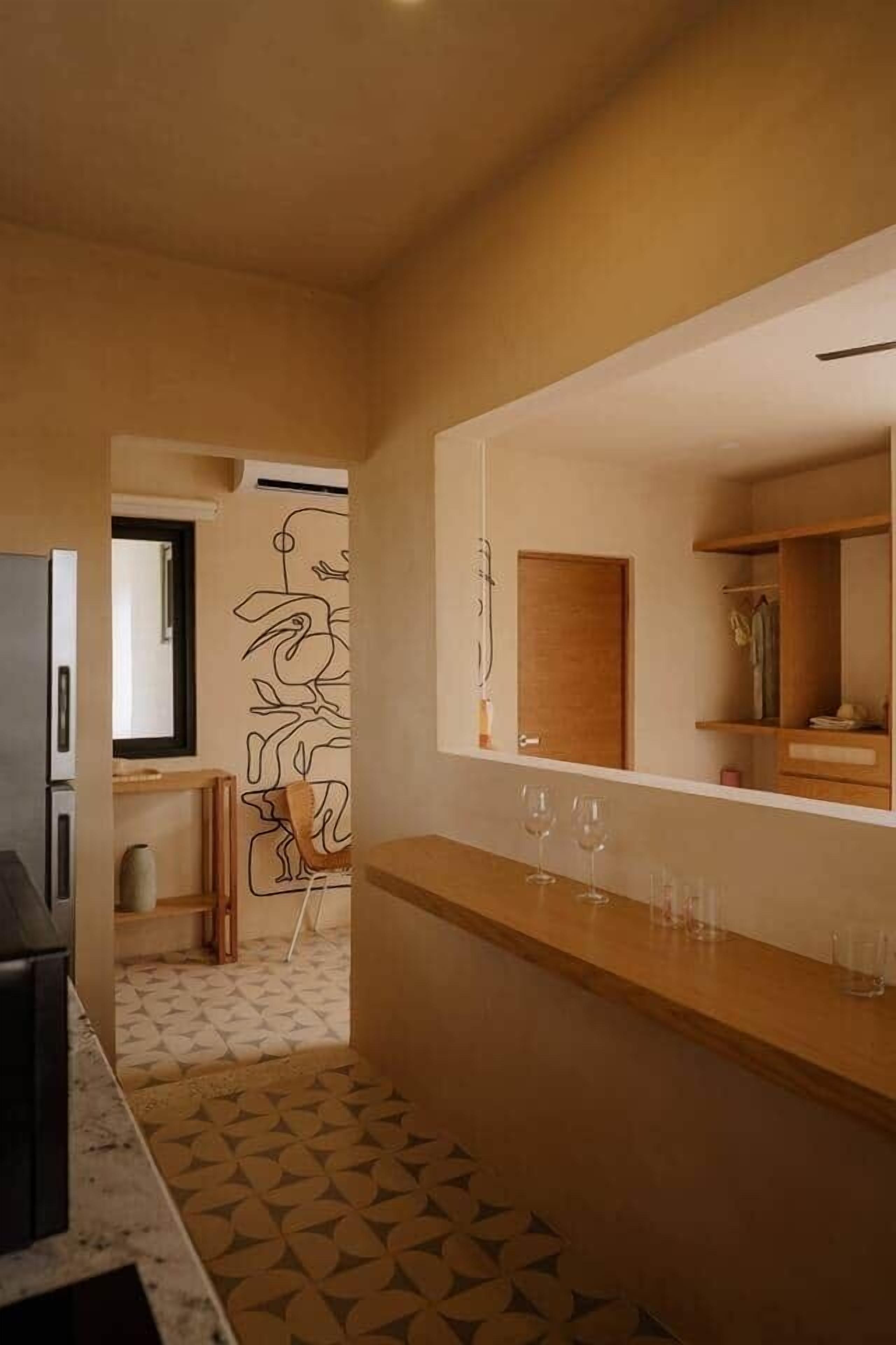 Une cuisine moderne dotée d’un long plan de travail, d’un réfrigérateur et d’un sol à motifs.