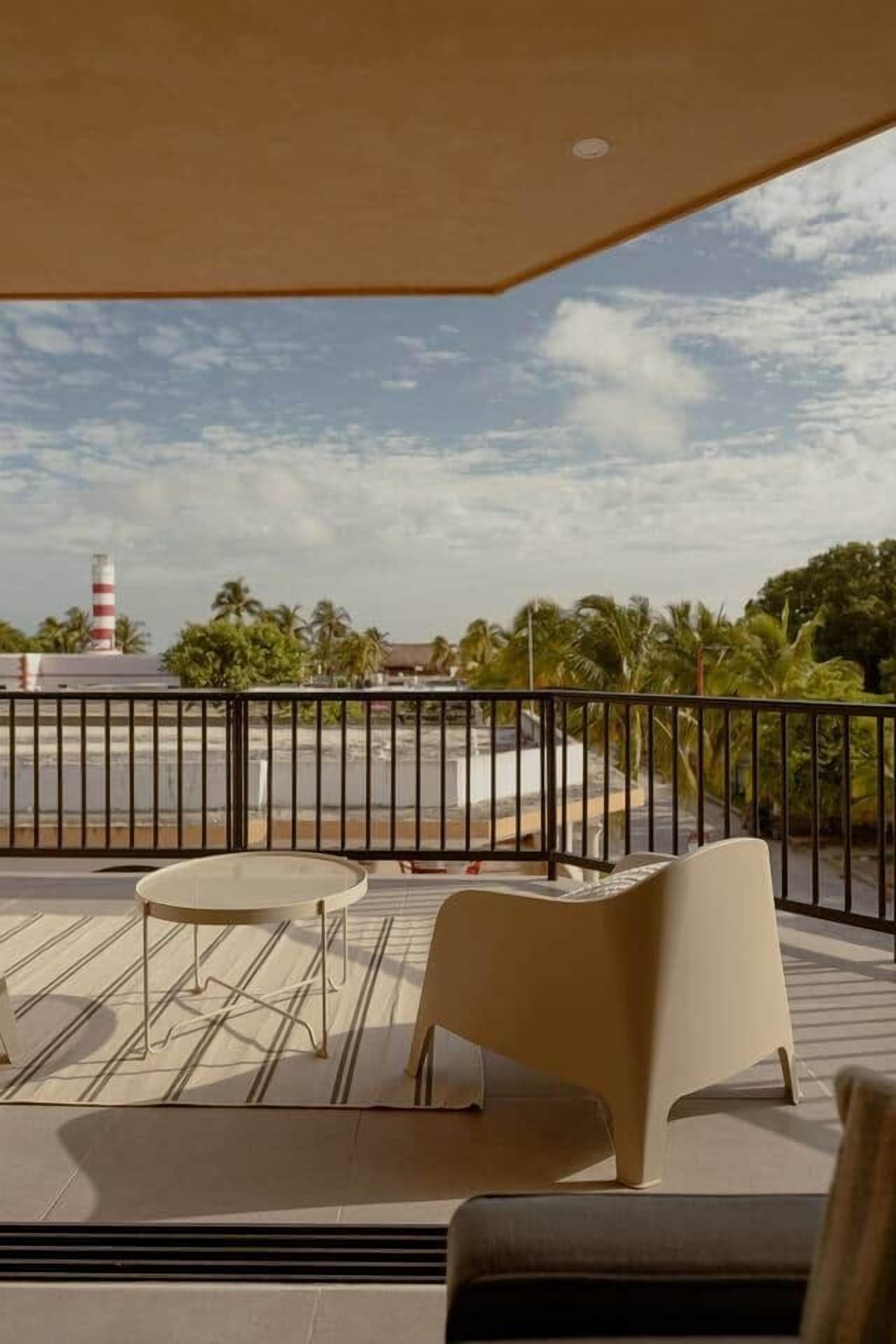 Un balcon donnant sur une rue, des palmiers et un phare.