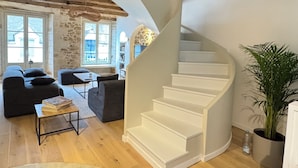 Un intérieur moderne avec un escalier en colimaçon, un mur en pierre et une vue dégagée grâce à de grandes fenêtres.