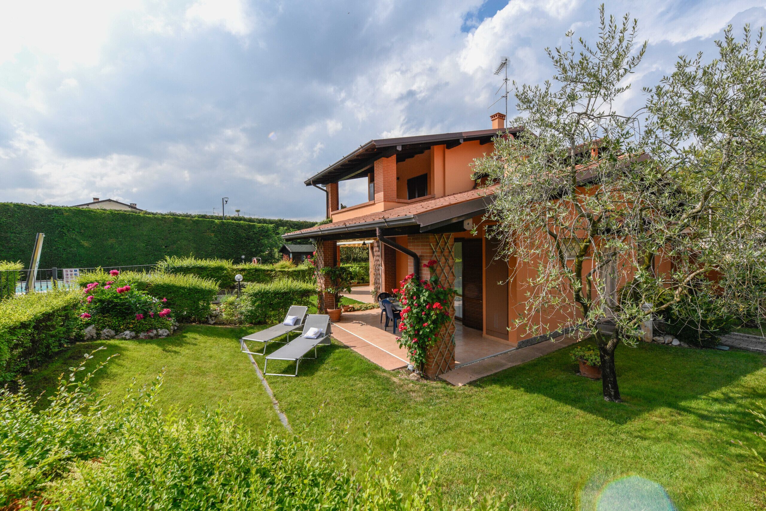 A house with a patio, a lawn, and a garden.