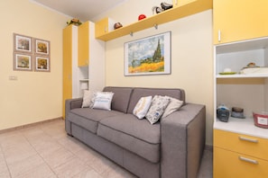 Ein Wohnzimmer mit einer Couch, einem Gemälde und einem gelben Schrank.