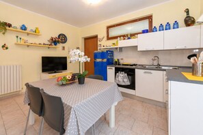 A compact kitchen with a dining area, a television, and various kitchen appliances. - MGH - Garda Bloom Family Stay Manerba (Manerba del Garda)