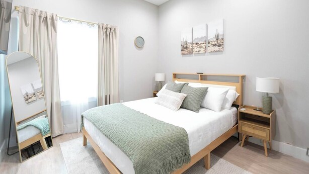 A bedroom with a bed, bedside tables, a mirror, and a window with curtains. - Stockyards + Downtown | Bright 1BR | Sleeps 3 - Apartment (Fort Worth)