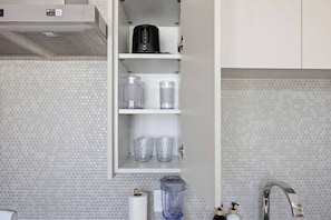 A kitchen with a microwave, a coffee maker, and a blender on the counter.