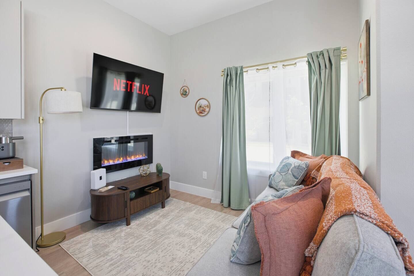 Ein modernes Wohnzimmer mit Flachbildfernseher, Kamin, einer Couch und einem Essbereich mit einer Lampe.