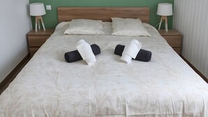 Un llit ben tendrat amb un estovat estampat floral, dues làmpades de nit i una paret verda.