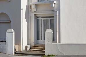 Un edificio blanco con una puerta de garaje, unos escalones que conducen a una puerta y un pequeño porche.