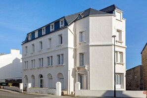 A multi-story building with a flat roof, multiple windows, and a white facade. - Bright Apartment Near the Sea with Wi-Fi (Penmarch)