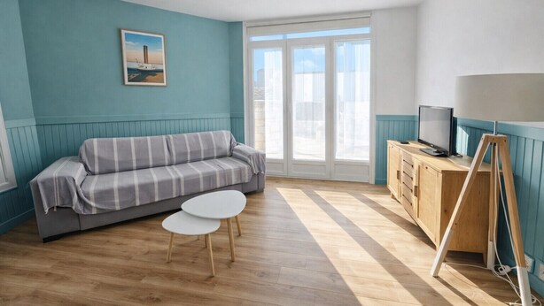 Habitació amb un sofà, una taula petita, una televisió i un quadre a la paret.