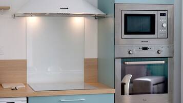 A kitchen with a built-in microwave, oven, and a range hood above the stove.