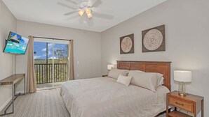 A hotel room with a bed, a TV, a ceiling fan, a nightstand, and a balcony with a view. - Upstay Large Family Condo w Pool, Sauna (Winter Garden)