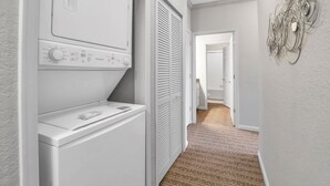 A laundry room with a washing machine, dryer, and a wall-mounted decorative piece. - Upstay Large Family Condo w Pool, Sauna (Winter Garden)