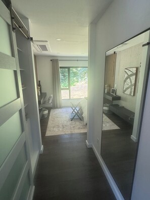 A narrow hallway with a large mirror, a window with curtains, and a small seating area with a rug. - Experience elevated living in a magnificent brand new modern home set on 5 acres (Clinton Corners)