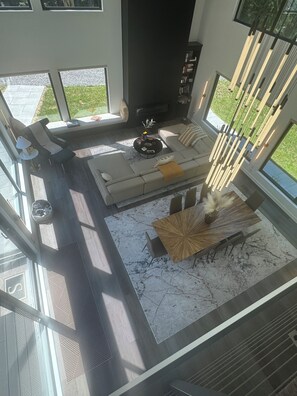 A modern living room with a sofa, coffee table, and dining table. - Experience elevated living in a magnificent brand new modern home set on 5 acres (Clinton Corners)