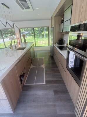 Eine moderne Küche mit großem Fenster, Edelstahlgeräten und einem minimalistischen Design.
