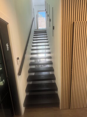 Eine Treppe mit Handlauf, eine Tür mit Griff und ein Fenster im Obergeschoss.