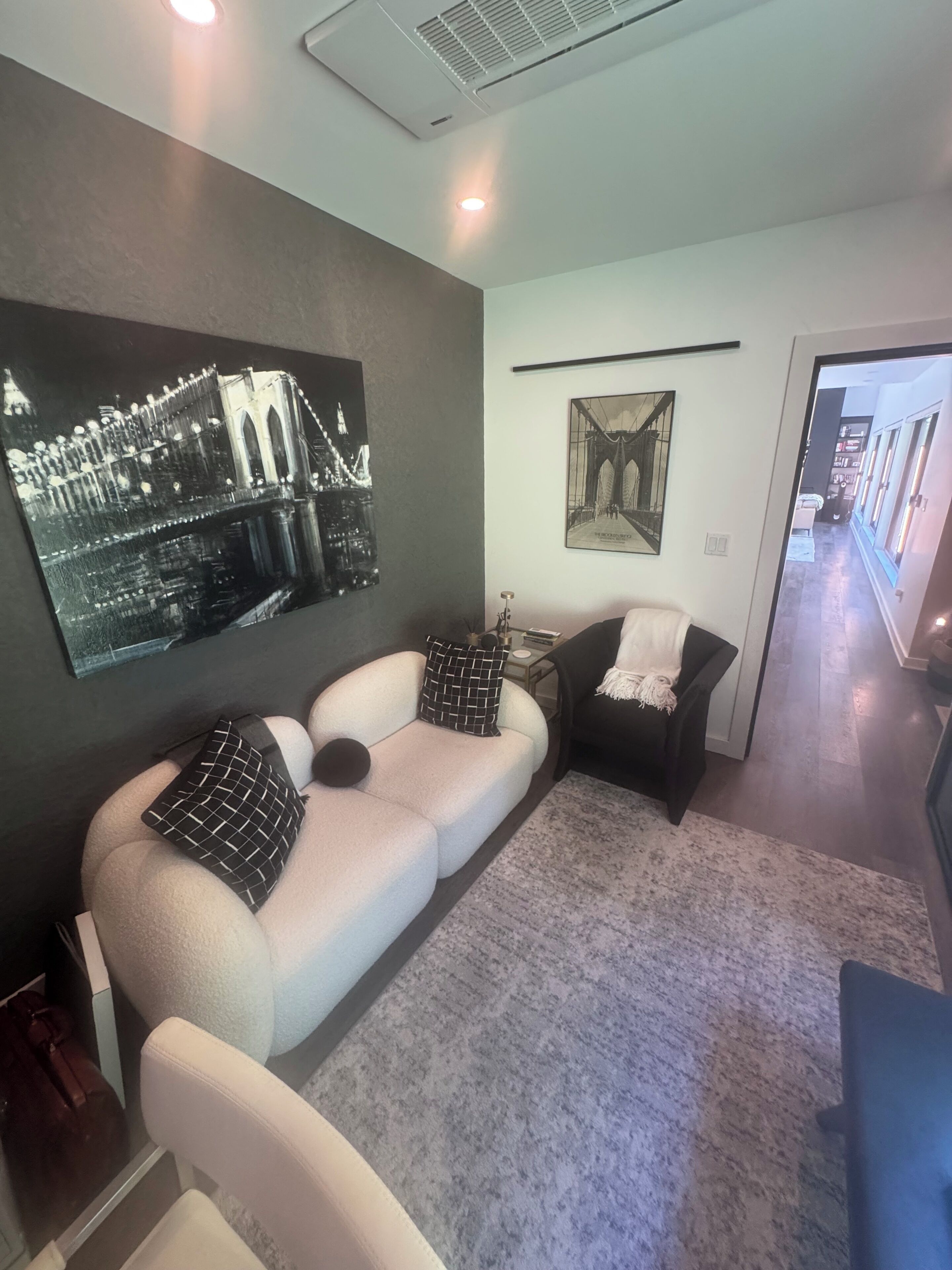 Un salon moderne avec un canapé d’angle, une petite table d’appoint et deux tableaux accrochés au mur.