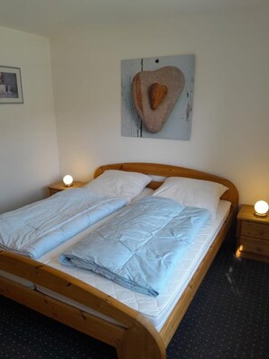 A single bed with a wooden frame, white bedding, and two bedside lamps. - NEW! Vacation Rental "Nordseeanker 2c" (Dornum)