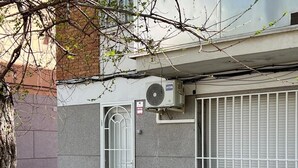 Een gebouw met een hek, een beveiligingscamera en een airconditioning op de muur.