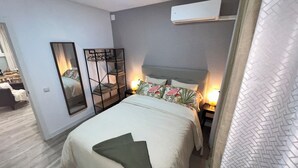 Een hotelkamer met een bed, nachtkastje, airconditioning en een spiegel.