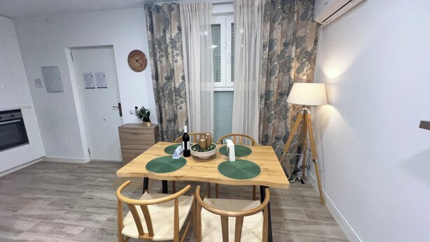 Een eetruimte met een houten tafel, vier stoelen, een lamp en een klok aan de muur.