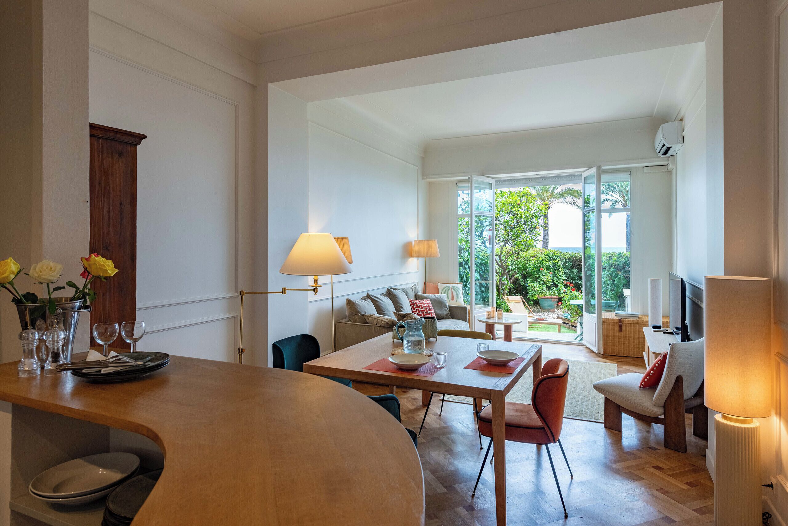 A modern living room with a dining area, a sofa, and a TV.