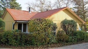 A single-story house with a red-tiled roof, surrounded by dense foliage and trees. - Gemutlicher Doppelbungalow mit Garten und Kaminofen in Mirow (Mirow)