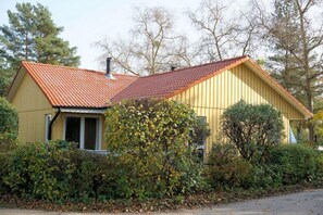 A single-story house with a red-tiled roof, surrounded by dense foliage and trees. - Gemutlicher Doppelbungalow mit Garten und Kaminofen in Mirow (Mirow)