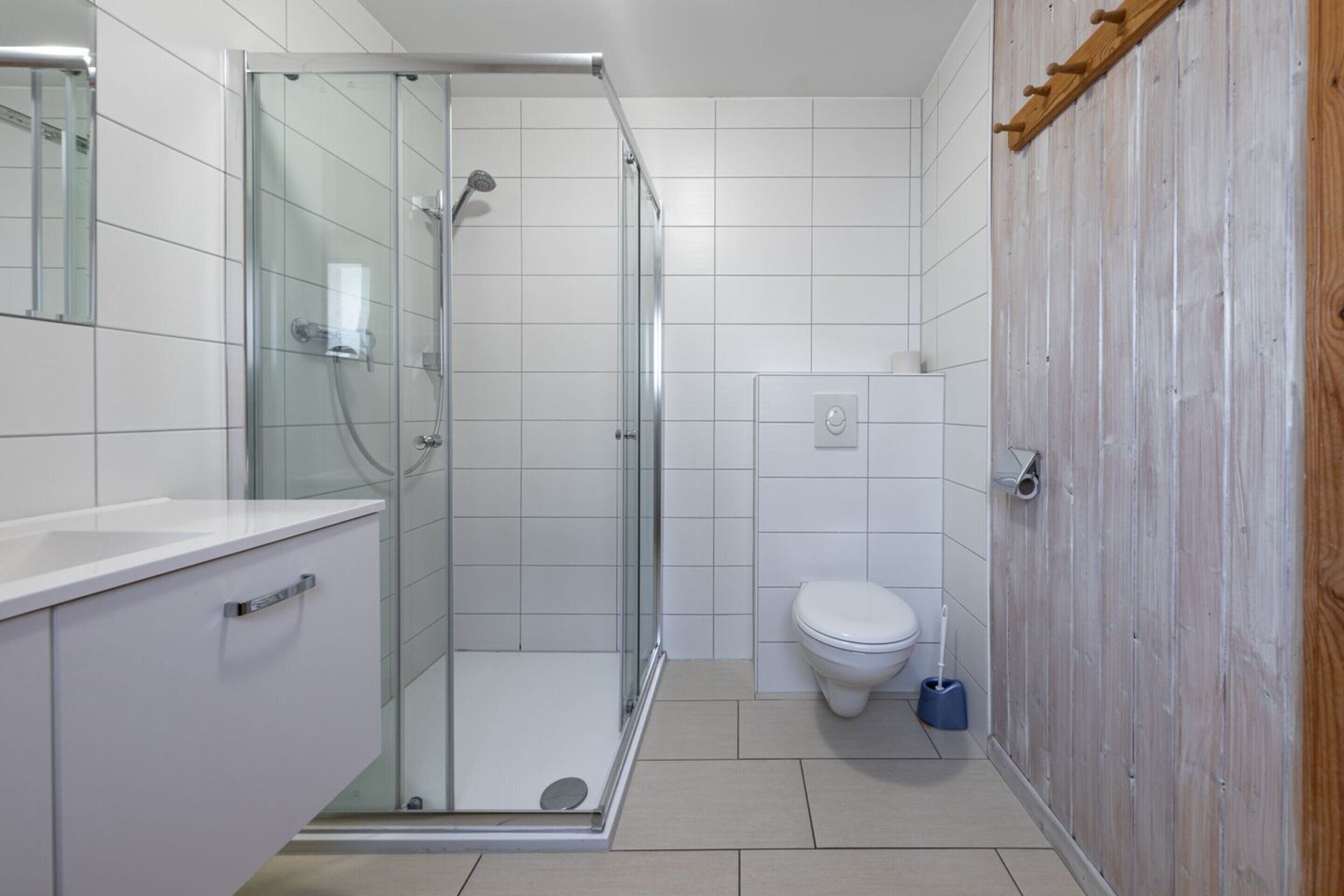 Ein modernes Badezimmer mit einer Glasdusche, einer Toilette und einer Holzwand.