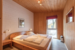 Habitació amb panells de fusta, un llit, una làmpada penjada a la paret i una finestra.