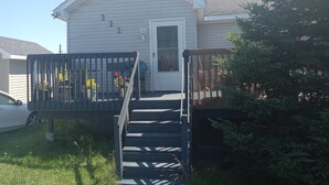 A residential house with a front porch, a door, and a staircase leading to the entrance. - Country in the City: Quiet, central home with golf views, near Victoria Park. (Truro)