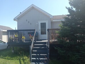 A residential house with a front porch, a door, and a staircase leading to the entrance. - Country in the City: Quiet, central home with golf views, near Victoria Park. (Truro)