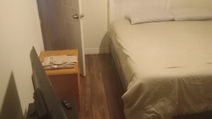 A bedroom with a bed, a wooden nightstand, and a television. - Country in the City: Quiet, central home with golf views, near Victoria Park. (Truro)