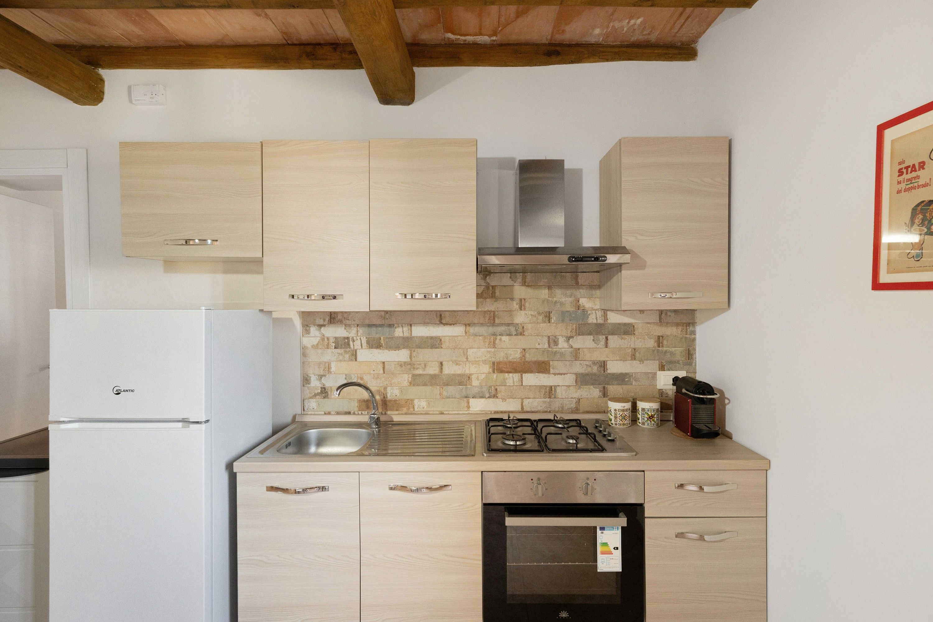 Une cuisine avec des meubles en bois, un évier en acier inoxydable, une cuisinière à gaz et un four encastré.