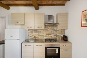 Une cuisine avec des meubles en bois, un évier en acier inoxydable, une cuisinière à gaz et un four encastré.