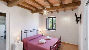 Une chambre à coucher avec un lit, des tables de chevet, une fenêtre et un ventilateur de plafond.