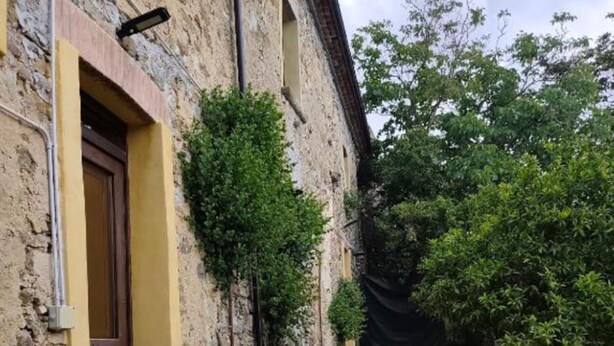 A stone pathway leading to a building with a wooden door and a yellow wall. - Giardino Siniscalchi – Apartment 1 with Wi-Fi and Air Conditioning (Copersito)