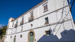 A white building with a green door, multiple windows, and a balcony. - Giardino Siniscalchi – Apartment 1 with Wi-Fi and Air Conditioning (Copersito)