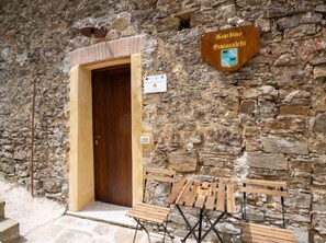 A stone building with a wooden door, a sign reading 'Giardino Siniscalchi,' and outdoor wooden benches.