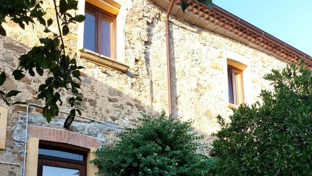 A stone building with a wooden door, steps leading to the entrance, and a large terracotta planter with plants. - Giardino Siniscalchi Apartment 2 with Wi-Fi and Air Conditioning (Copersito)