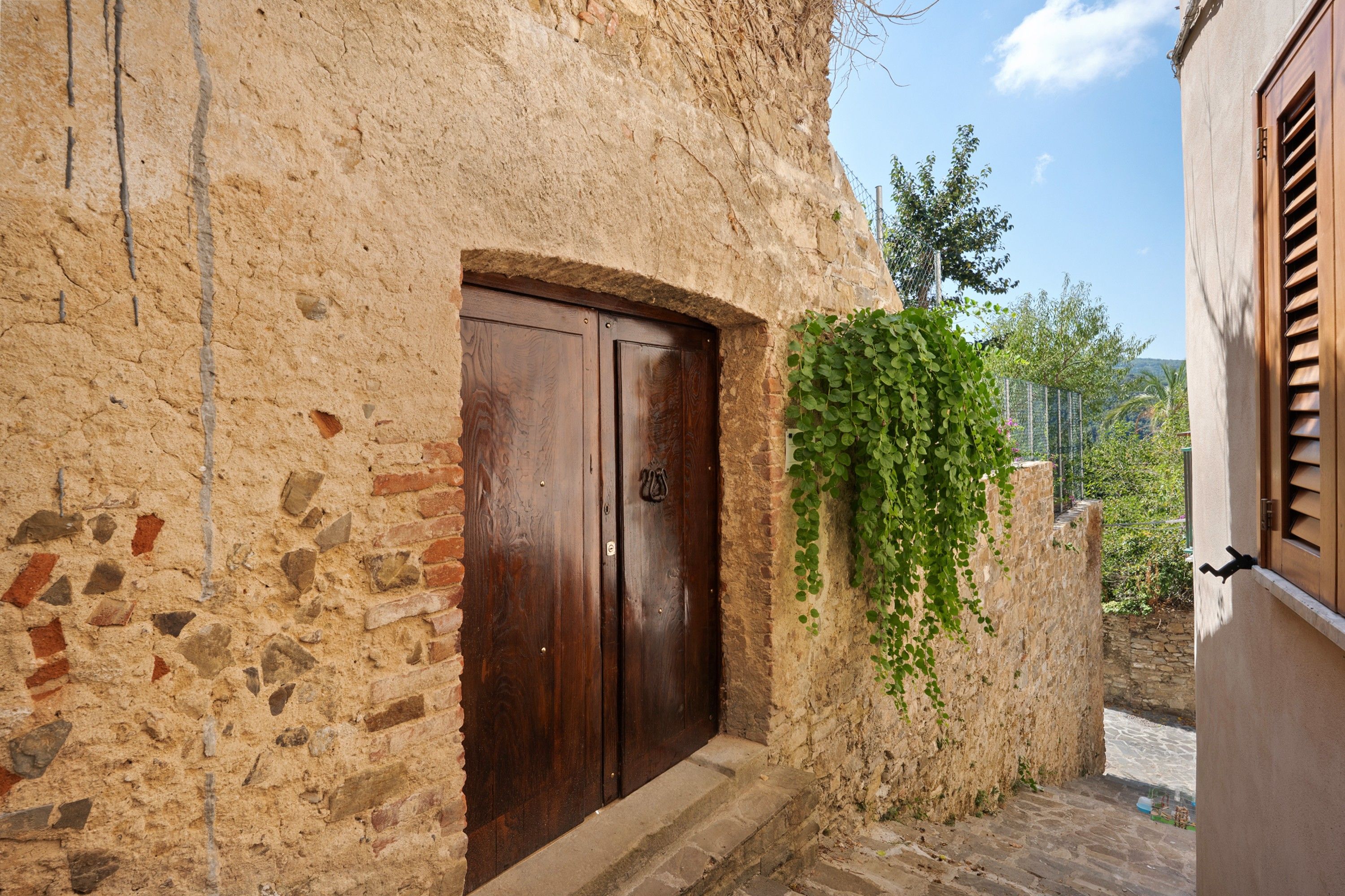 Un bâtiment rustique en pierre, doté d’une porte en bois et d’un petit escalier en pierre menant à l’entrée.