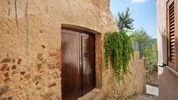Un bâtiment rustique en pierre, doté d’une porte en bois et d’un petit escalier en pierre menant à l’entrée.