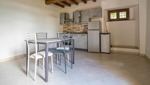 A kitchen with a tiled floor, a dining table with chairs, and a window with a view. - Giardino Siniscalchi Apartment 2 with Wi-Fi and Air Conditioning (Copersito)