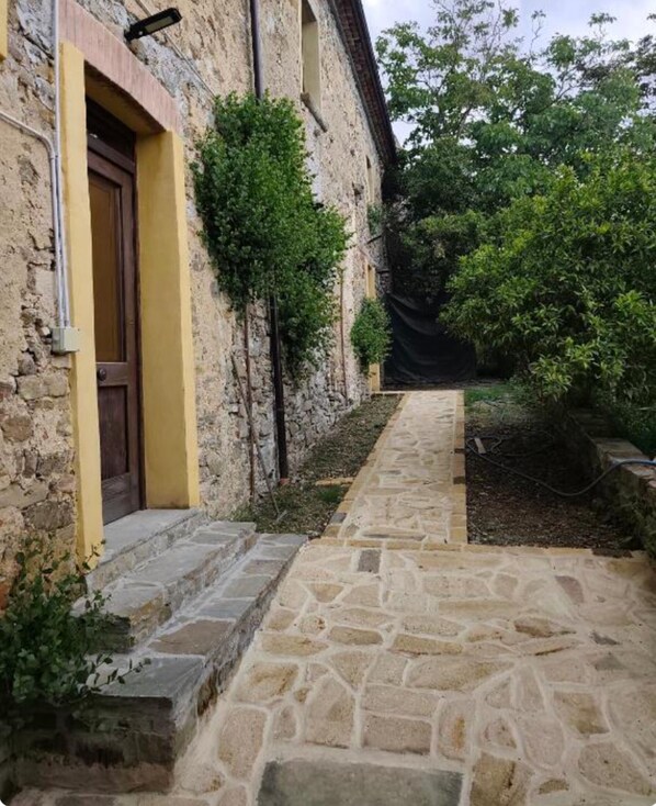 Un sendero de piedra que conduce a un edificio con una puerta de madera y escalones.
