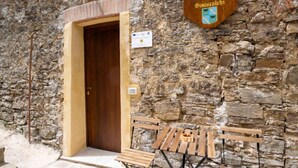 A stone building with a wooden door, a sign reading 'Giardino Siniscalchi,' and outdoor wooden benches. - Giardino Siniscalchi Apartment 2 with Wi-Fi and Air Conditioning (Copersito)
