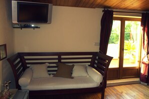 A room with a wooden bench sofa, a flat-screen TV mounted on the wall, and a sliding glass door leading to an outdoor area.